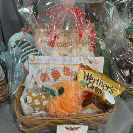 Gift basket with snacks, a jar, and a pumpkin-themed item wrapped in clear cellophane