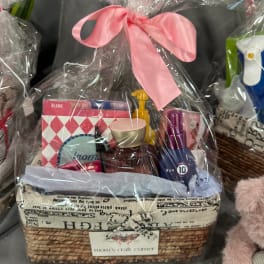 Gift basket with toiletries and greeting cards wrapped in clear plastic and a pink bow