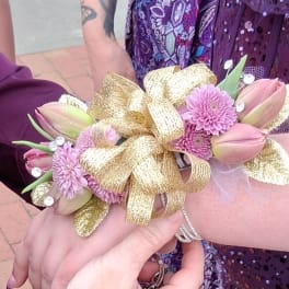 Pink tulip corsage with purple daisies and a gold ribbon bow