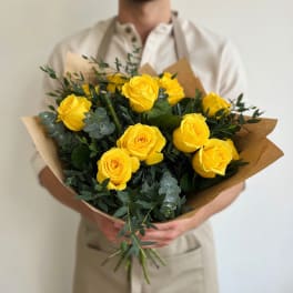 Bouquet of yellow roses wrapped in brown paper