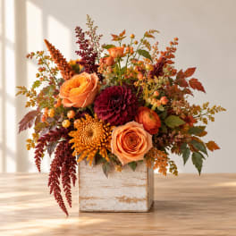 Autumn floral arrangement in a rustic wooden box with orange and burgundy blooms