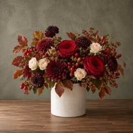 Red roses and burgundy mums in a white vase with autumn berries