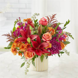 Colorful bouquet of lilies, roses, and mums in a striped vase