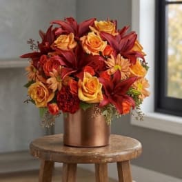 Red and orange floral arrangement in a copper vase