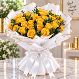 Bouquet of yellow roses wrapped in white paper with gold trim and a white ribbon