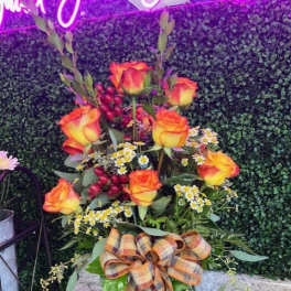 Tall bouquet of orange-yellow roses in a glass vase with a plaid ribbon