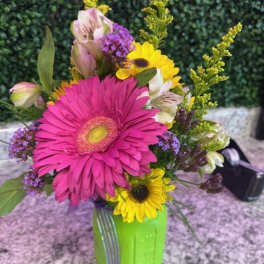 Bright mixed bouquet in a green mason jar with pink and yellow blooms