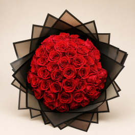 Round bouquet of red roses wrapped in black paper