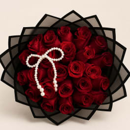 Bouquet of red roses wrapped in black paper with a pearl necklace