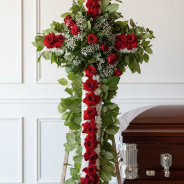 Red rose funeral cross arrangement on an easel beside a casket