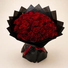 Large bouquet of red roses wrapped in black paper with a red ribbon