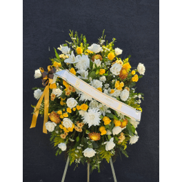 Large white and yellow floral standing spray with a ribbon sash