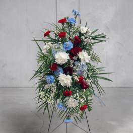Standing floral spray with red, white, and blue flowers on a metal easel