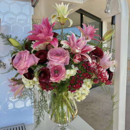 Pink lilies and roses arranged in a clear glass vase