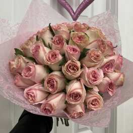 Bouquet of pale pink roses wrapped in pink paper with a glittery heart ornament