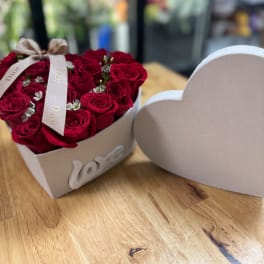 Heart-shaped box of red roses with a ribbon on a wooden table