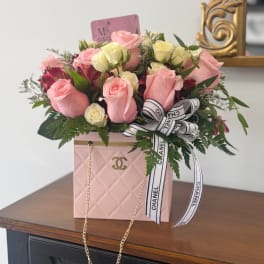 Pink and cream rose arrangement in a pink box with a Chanel ribbon