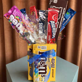 Assorted candy bars arranged like a bouquet with a blue ribbon