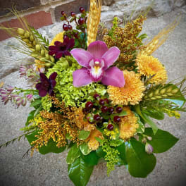 Mixed bouquet with pink orchid, yellow mums, and wheat stems