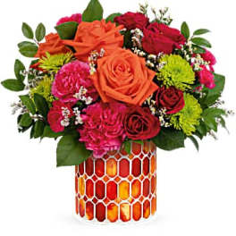 Mixed bouquet of orange, red, and pink flowers in a patterned vase