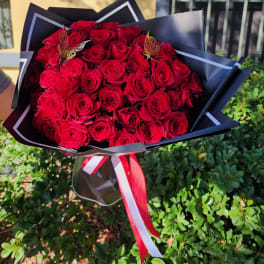 Bouquet of red roses wrapped in black paper with red and white ribbon