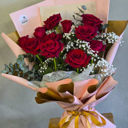 Bouquet of red roses with baby's breath in pink and gold wrapping