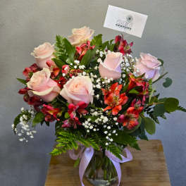 Bouquet of pale pink roses and red alstroemeria in a glass vase