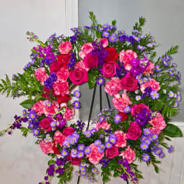 Heart-shaped floral wreath with pink roses, carnations, and purple daisies