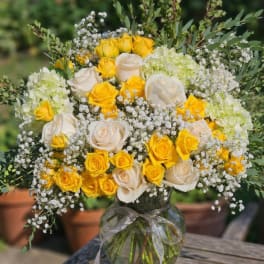 Bouquet of yellow and white roses in a glass vase with baby's breath