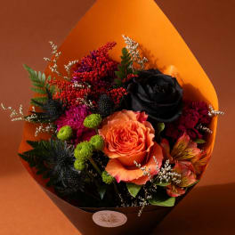 Bouquet with orange and black roses, magenta blooms, and orange wrap