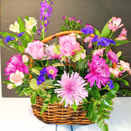 Basket arrangement of pink roses, chrysanthemums, and mixed blooms