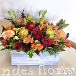 Mixed bouquet of red and orange flowers in a white wooden box