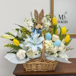 Basket arrangement with white lilies, yellow tulips, and a bunny topper