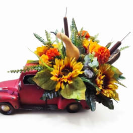 Sunflower and autumn floral arrangement in a red vintage truck container