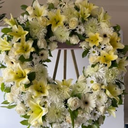 Heart-shaped floral wreath with yellow lilies, white roses, and white daisies