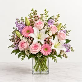 Pink roses, white lilies, and gerbera daisies in a clear glass vase