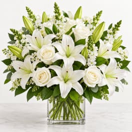 White lilies and roses arranged in a clear glass vase