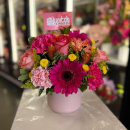 Bright mixed bouquet in a pale pink vase with pink and yellow flowers