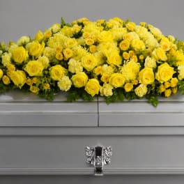 Yellow floral spray arranged on a silver casket