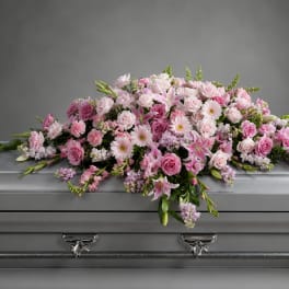 Pink floral spray arranged on a silver casket