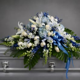 Blue and white floral casket spray with a satin ribbon