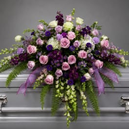Pink and purple floral spray on a silver casket