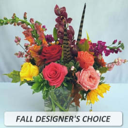 Mixed fall flower arrangement with roses, orchids, sunflowers and snapdragons in a clear glass vase