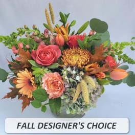 Round fall arrangement with orange roses, gerberas, and mums in a clear glass vase