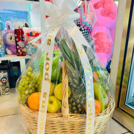 Gift basket of assorted fruit wrapped in clear cellophane with a white bow