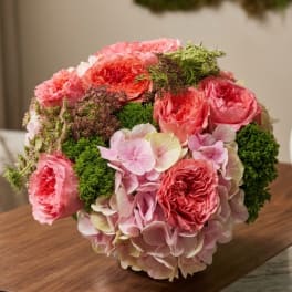 Pink rose and hydrangea bouquet with green filler in a low container