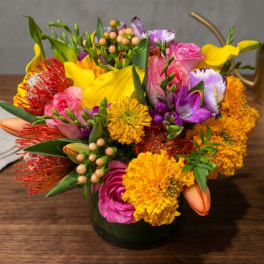 Colorful mixed bouquet in a dark vase with yellow, pink, purple, and orange blooms