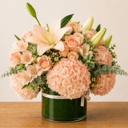 Peach bouquet with lilies, roses, and hydrangeas in a glass vase