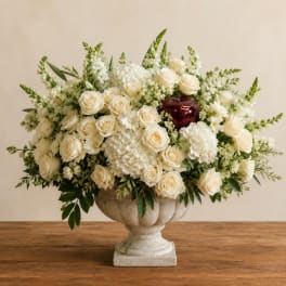 Cream roses and white flowers arranged in a stone urn