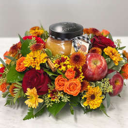 Autumn floral arrangement with apples and a jar candle in the center